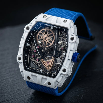 White tonneau skeleton watch at a three-quarter angle on dark slate, its ribbed blue crown beside the curved case
