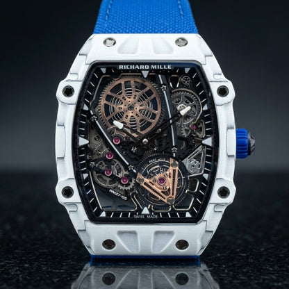 White tonneau tourbillon watch on a blue woven strap, worn on the wrist below a dark suit cuff