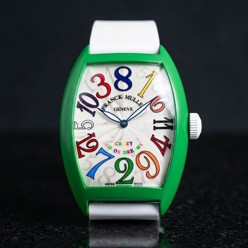 Green curved tonneau watch with a silver-white dial and multicoloured numerals out of order, upright on polished black granite