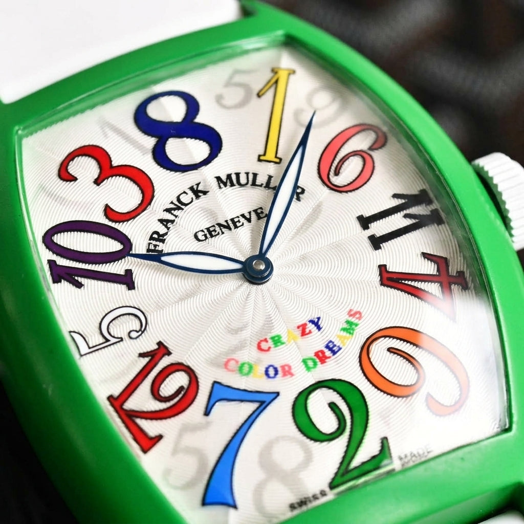 Macro of the silver-white sunray dial with large coloured numerals in a scrambled ring and blued hands
