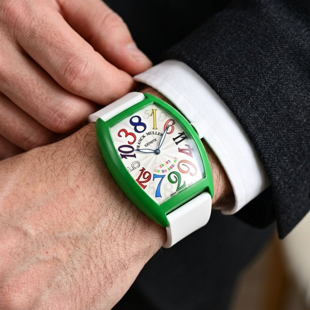 Green curved tonneau watch with rainbow numerals on a silver-white dial on the wrist as a shirt cuff is fastened