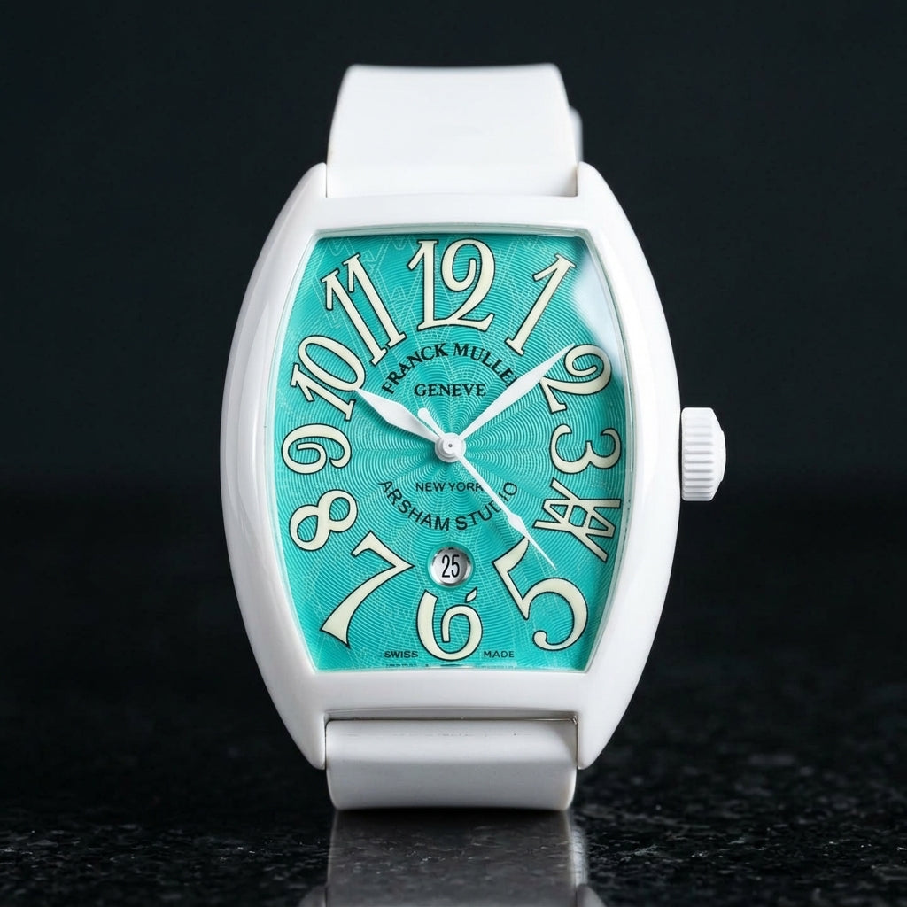 White curved tonneau watch with a turquoise dial and cream-white numerals, upright on polished black granite