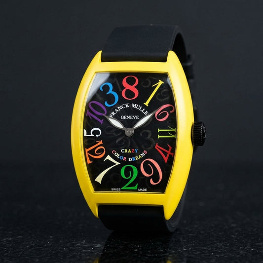 Yellow curved tonneau watch with a black dial and coloured numerals out of order, upright on polished black granite