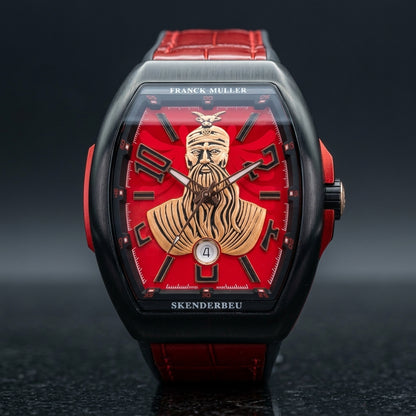 Black curved tonneau watch with a red dial on its red strap, worn on the wrist below a dark suit cuff