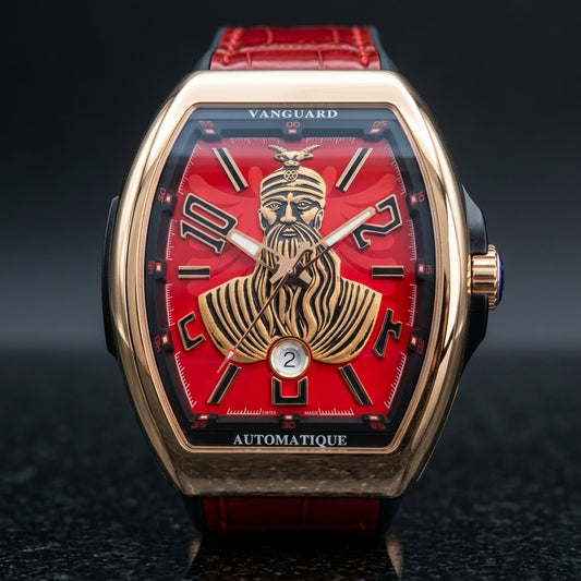 Rose gold curved tonneau watch with a red dial and a raised gold-tone warrior portrait, upright on polished black granite
