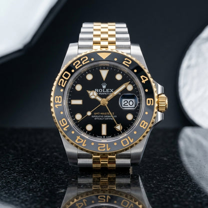 Two-tone steel and gold GMT watch with grey and black bezel on black granite