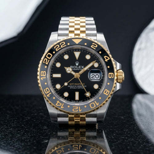 Two-tone steel and gold GMT watch with grey and black bezel on black granite