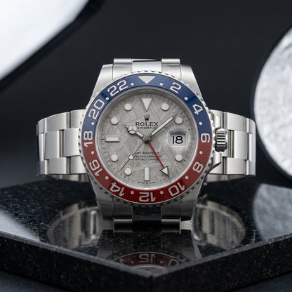 White metal GMT watch with meteorite dial and blue and red bezel on black granite