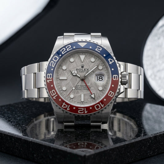 White metal GMT watch with meteorite dial and blue and red bezel on black granite