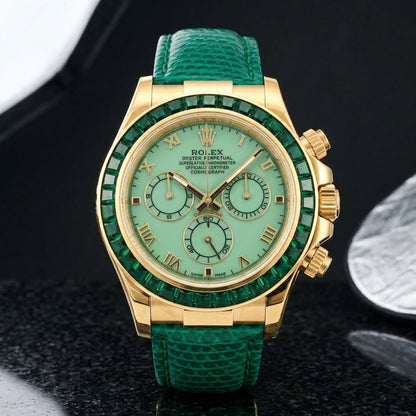 Gold-tone chronograph with a pale green dial, gold Roman numerals and a bezel of deep green baguette stones standing upright on polished black granite
