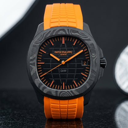 Black forged-carbon grid-dial watch with orange batons and a bright orange rubber strap, upright on polished black granite