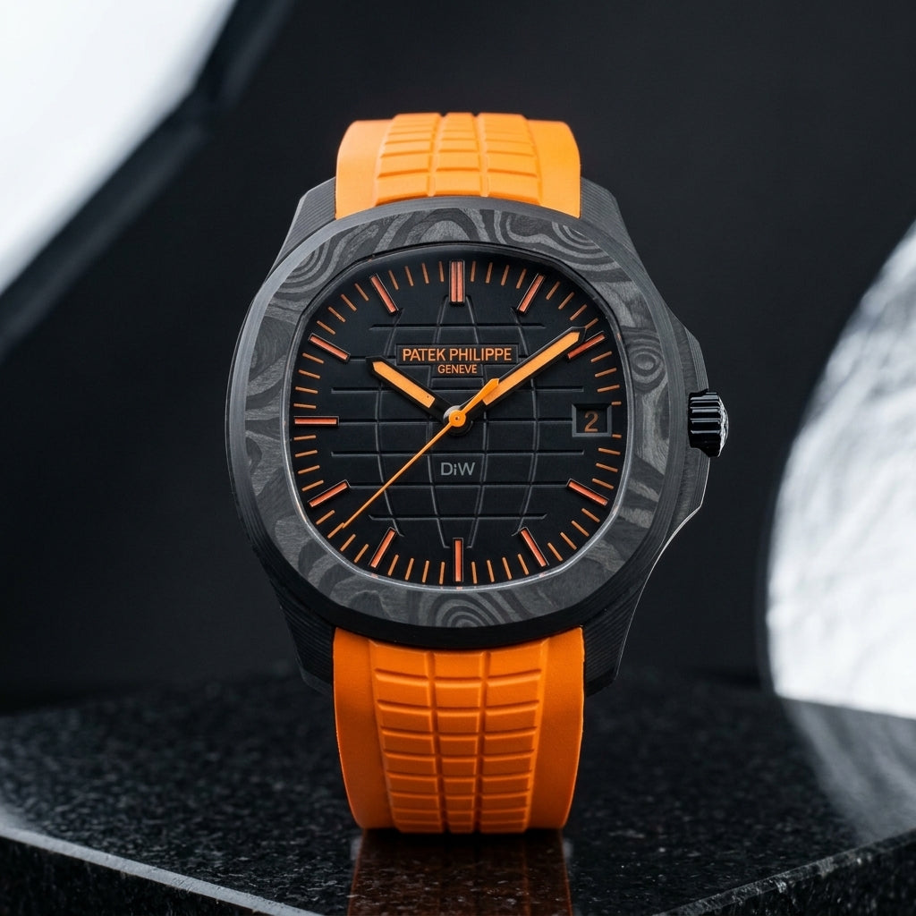 Black forged-carbon watch with an orange-on-black dial on a bright orange rubber strap, worn on the wrist below a navy suit cuff