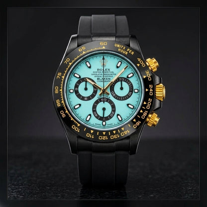 Black chronograph with a pale ice-blue dial and gold crown on black granite