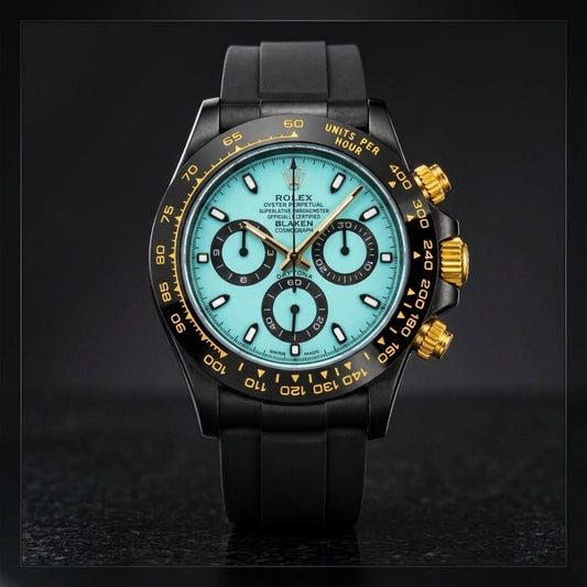 Black chronograph with a pale ice-blue dial and gold crown on black granite