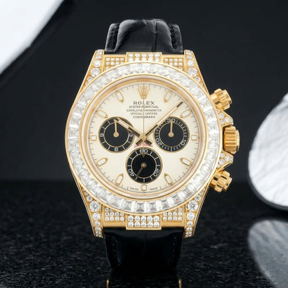 Yellow gold-wrapped chronograph with an ivory dial, three black counters and a clear moissanite baguette bezel standing upright on polished black granite