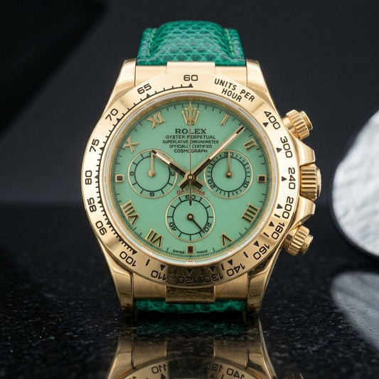 Gold-tone chronograph with a pale mint green dial, gold Roman numerals and an engraved tachymeter bezel standing upright on polished black granite