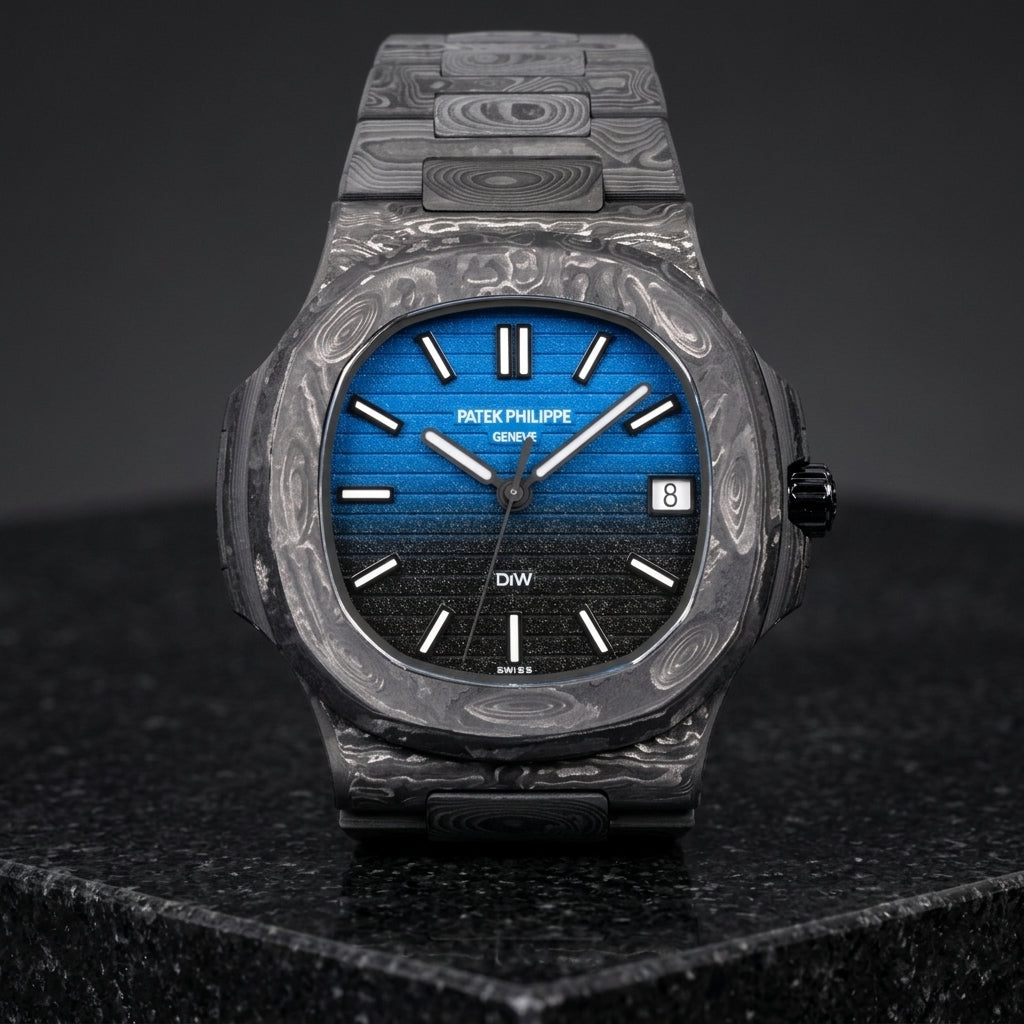 Forged carbon sports watch with a blue-to-black dial on its carbon bracelet, worn on the wrist below a dark suit cuff