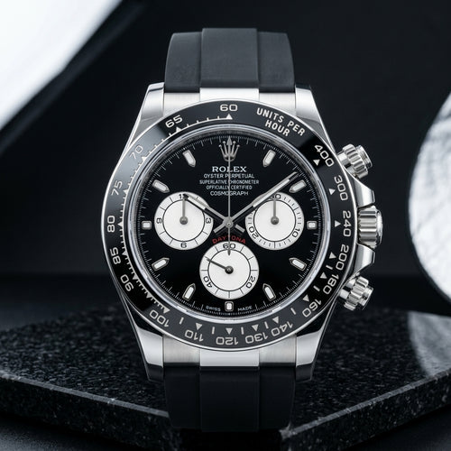 Steel chronograph with a black ceramic bezel, black dial and three white counters, upright on polished black granite