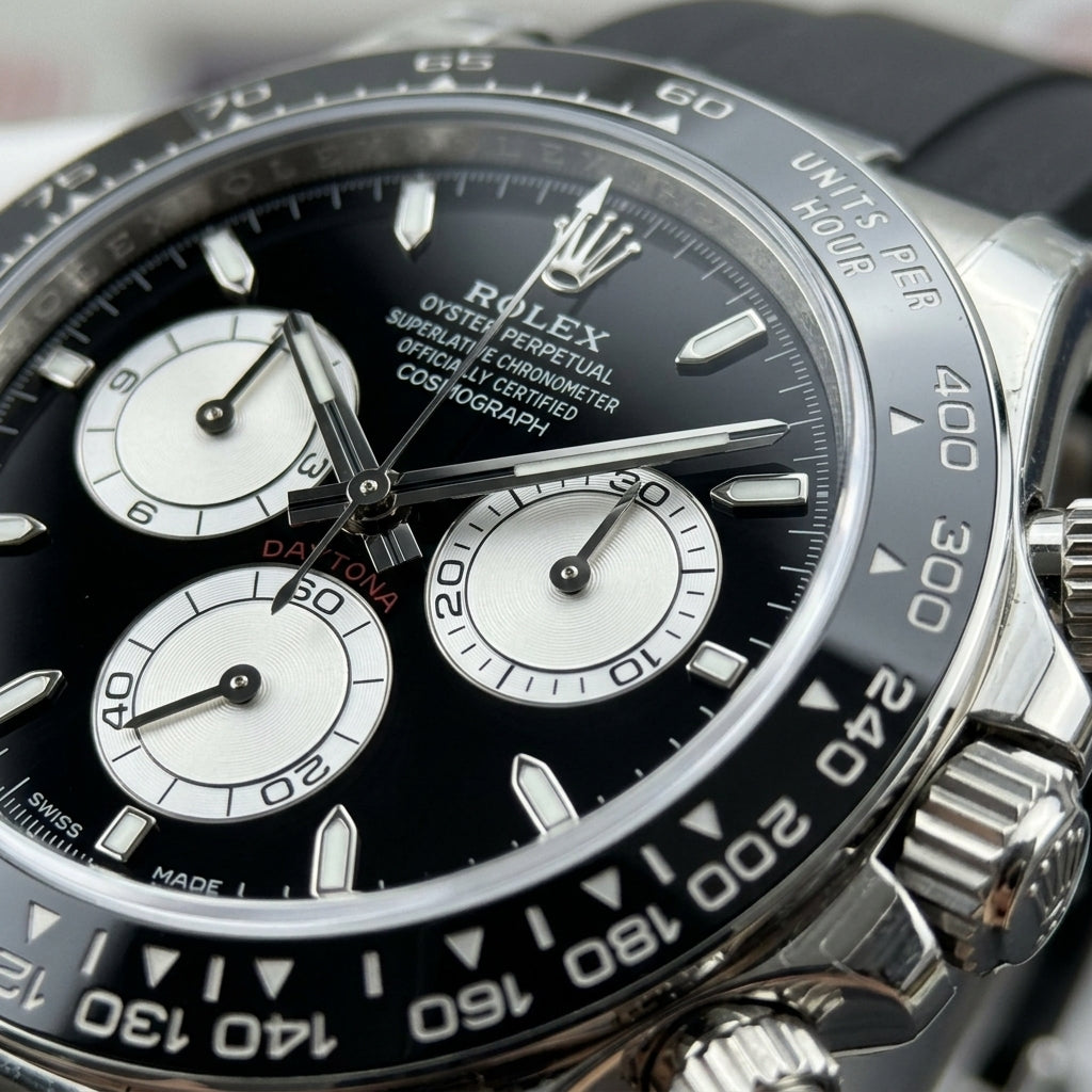 Macro of the black dial with three white counters ringed in black and steel baton markers with lume