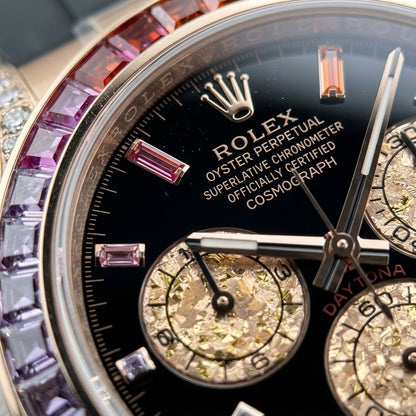 Macro of the black dial with rainbow baguette markers in rose-gold settings and three rose-gold counters textured like gold leaf