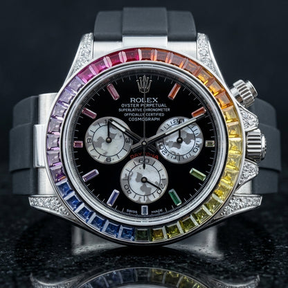 Steel chronograph with a rainbow baguette stone bezel and a black dial, upright on polished black marble