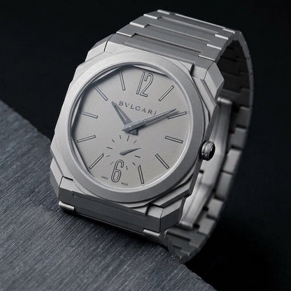 Ultra-thin titanium watch at a three-quarter angle on dark slate