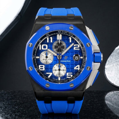 Blue ceramic chronograph on a blue rubber strap worn under a navy suit cuff