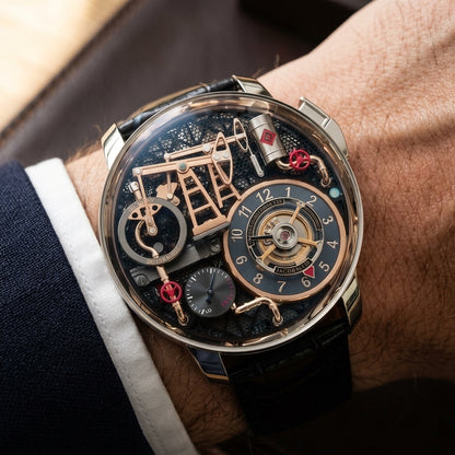 Oil pump watch with a silver case and black strap, worn under a navy suit cuff