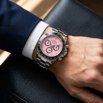 Pink-dial steel chronograph worn under a grey suit cuff