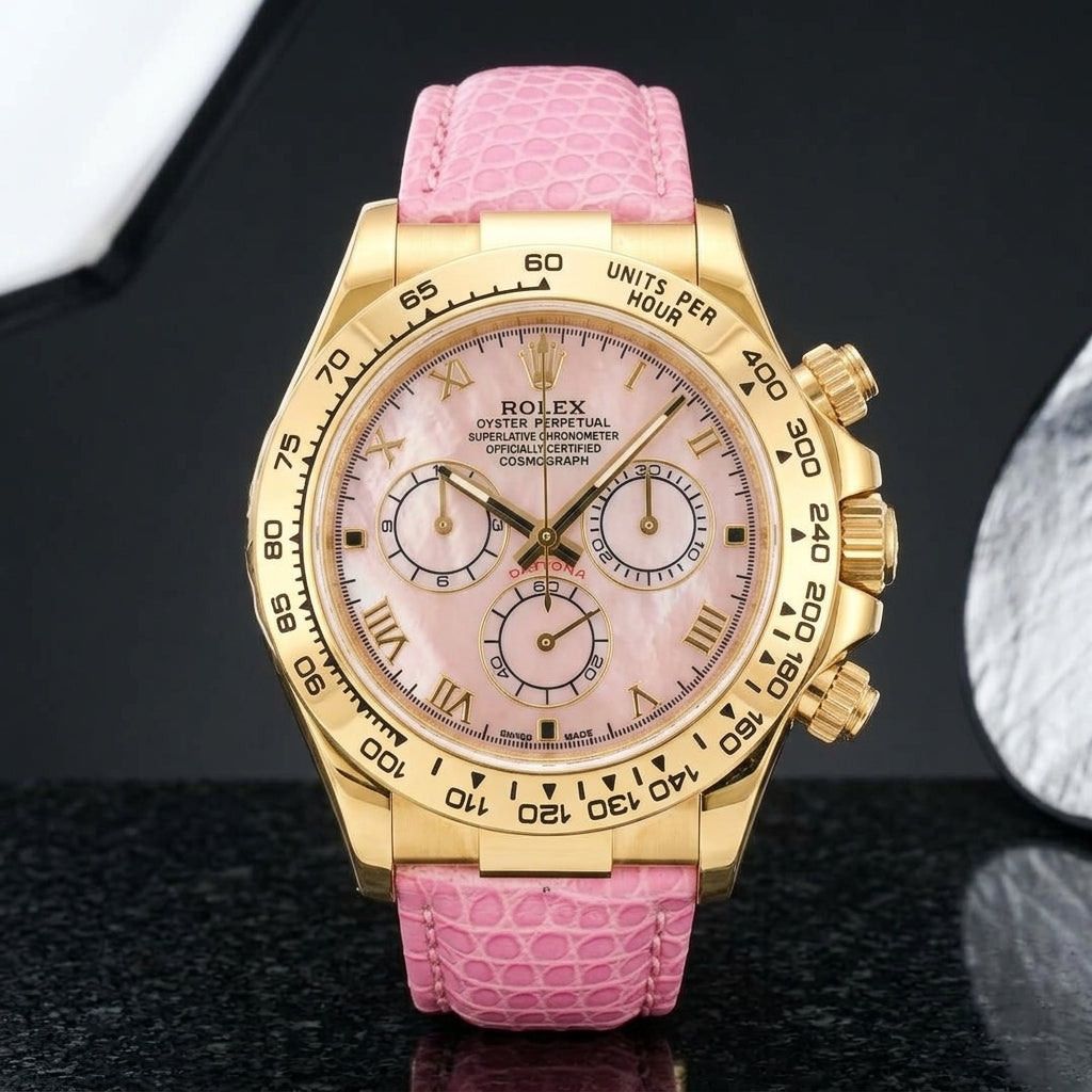 Gold-tone chronograph with a pink mother-of-pearl dial, gold Roman numerals and an engraved tachymeter bezel standing upright on polished black granite