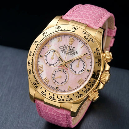 Gold-tone chronograph at a three-quarter angle on dark slate, its screw-down crown and fluted pushers beside a pink lizard-grain strap
