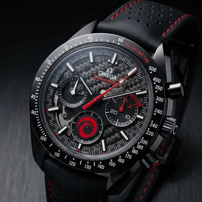 Black ceramic chronograph at a three-quarter angle on dark slate, its red-ended lower pusher below the black crown