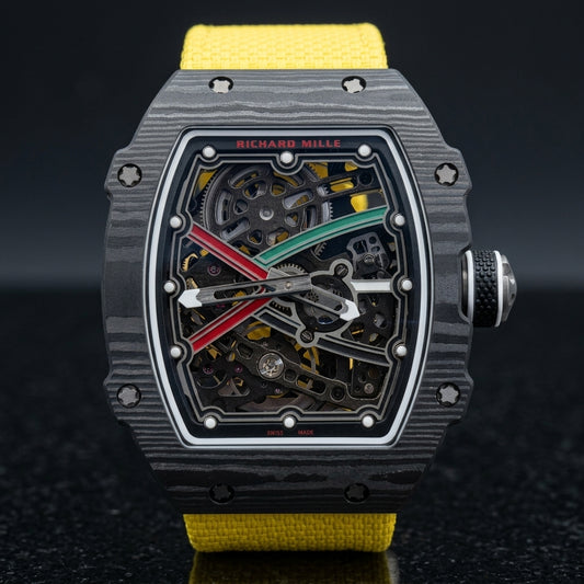 Ultra-thin black carbon tonneau watch with a skeleton dial, a red and green X and a bright yellow woven strap, upright on polished black granite