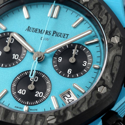 Macro of the sky-blue dial with steel baton markers and three black counters inside the black forged-carbon bezel and its steel screws
