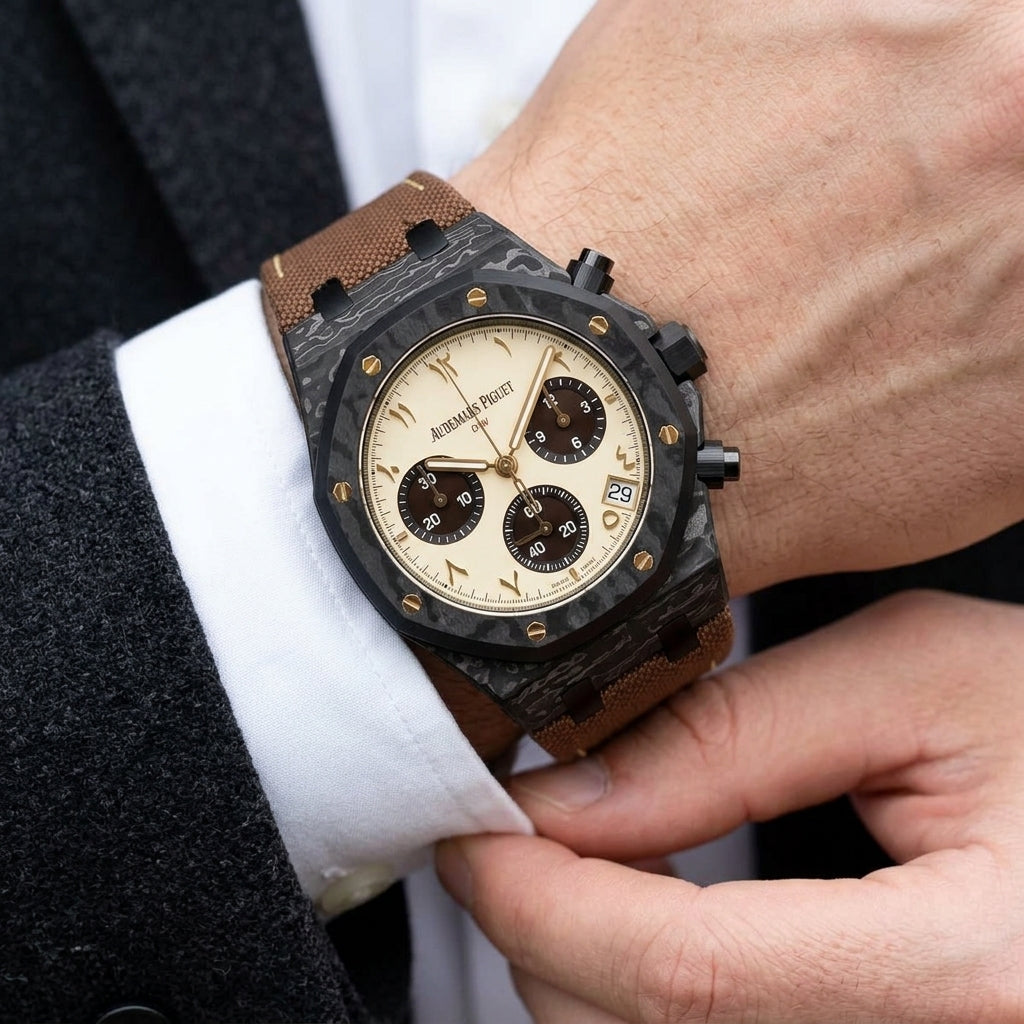 Black forged-carbon octagonal chronograph with a cream dial and gold Eastern Arabic numerals on the wrist as a shirt cuff is fastened
