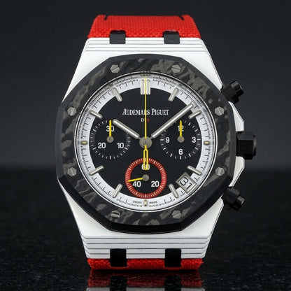 White octagonal chronograph with a black carbon bezel and a black dial, upright on polished black granite