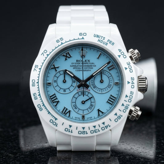 White ceramic chronograph with a light blue dial and steel Roman numerals, upright on polished white marble