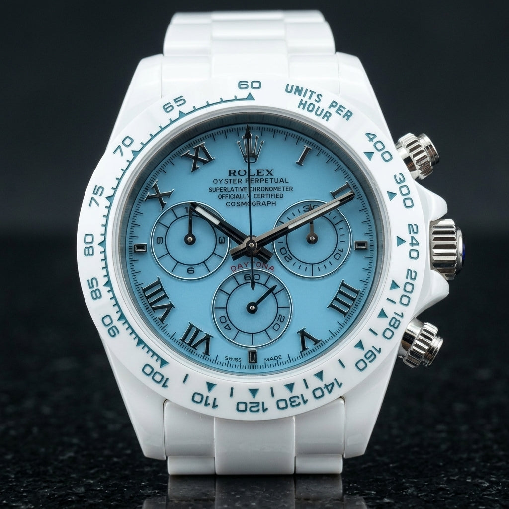 White ceramic chronograph with a light blue dial on its white ceramic bracelet, worn on the wrist below a dark suit cuff
