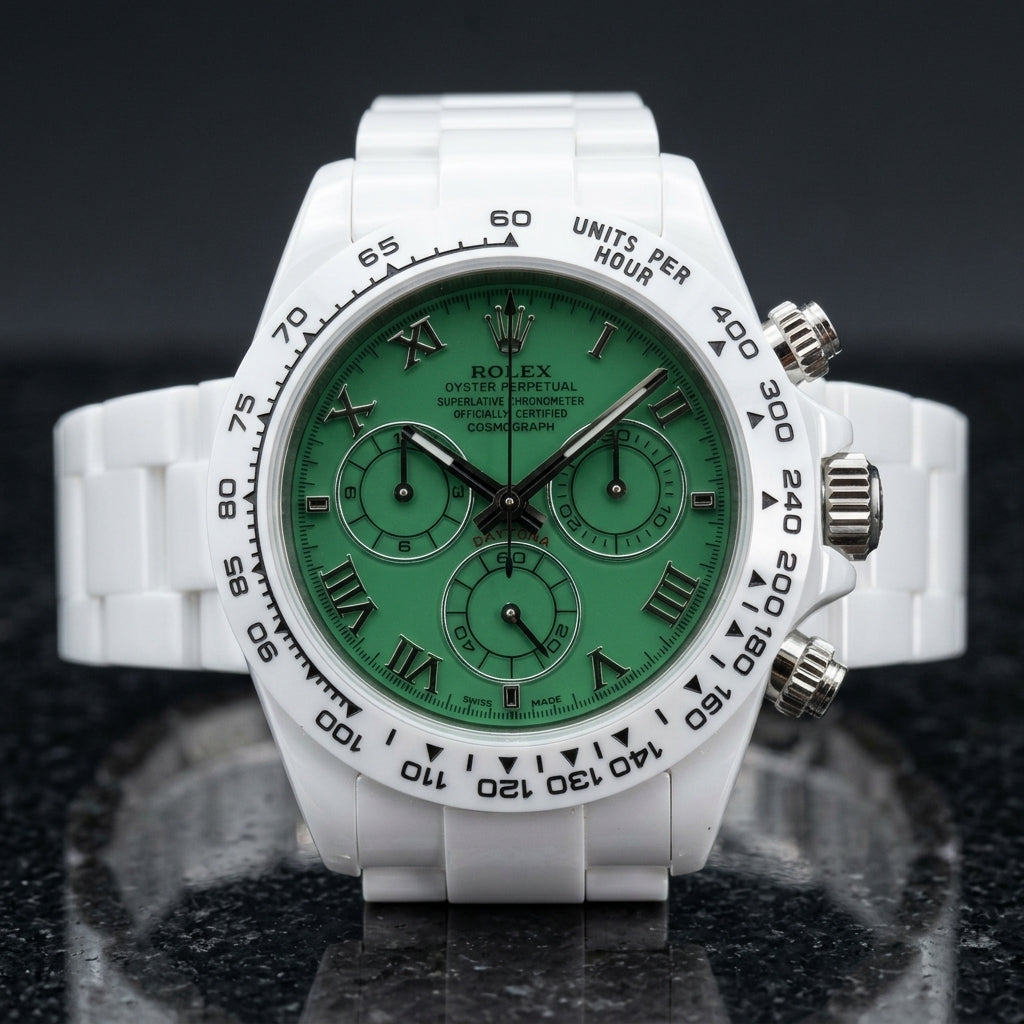 White ceramic chronograph with a green Roman numeral dial and a white tachymeter bezel, upright on polished black granite