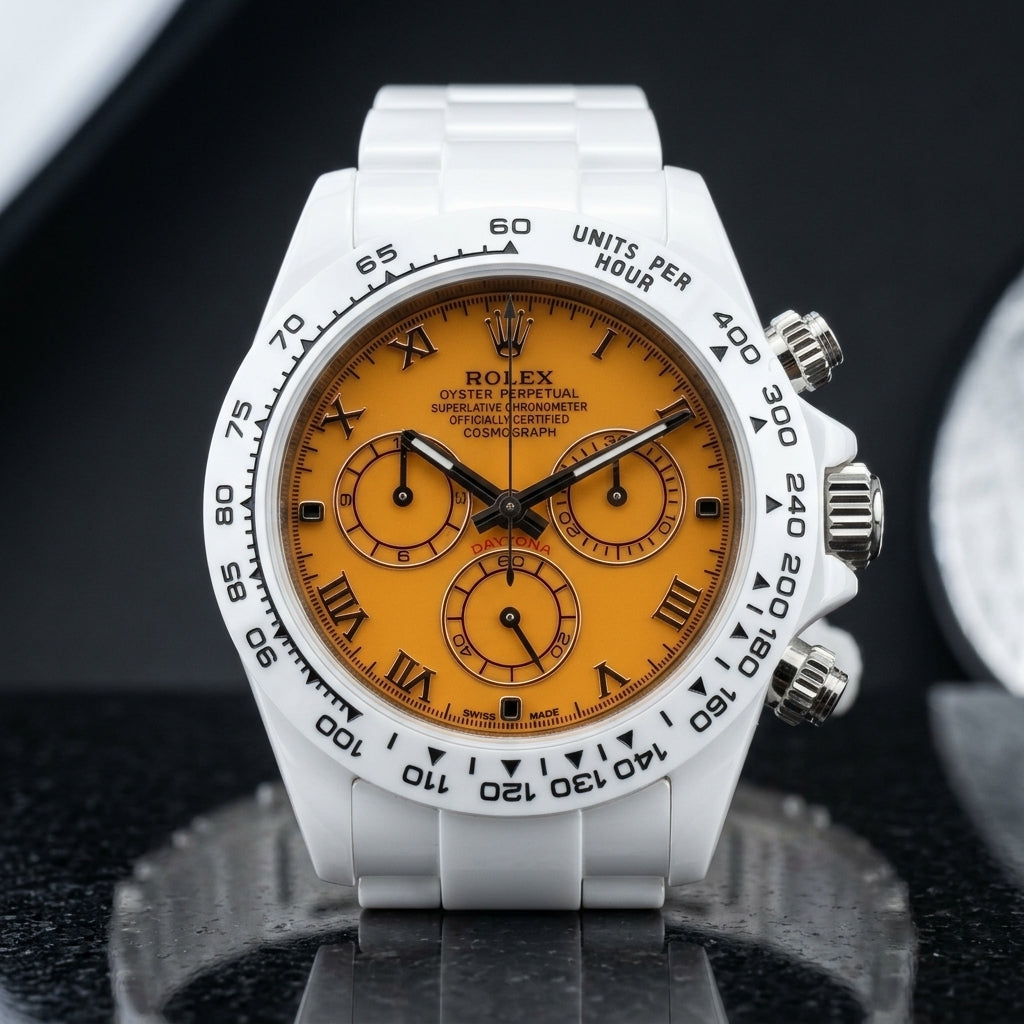White ceramic chronograph with a mango-orange dial and black Roman numerals, upright on polished black granite