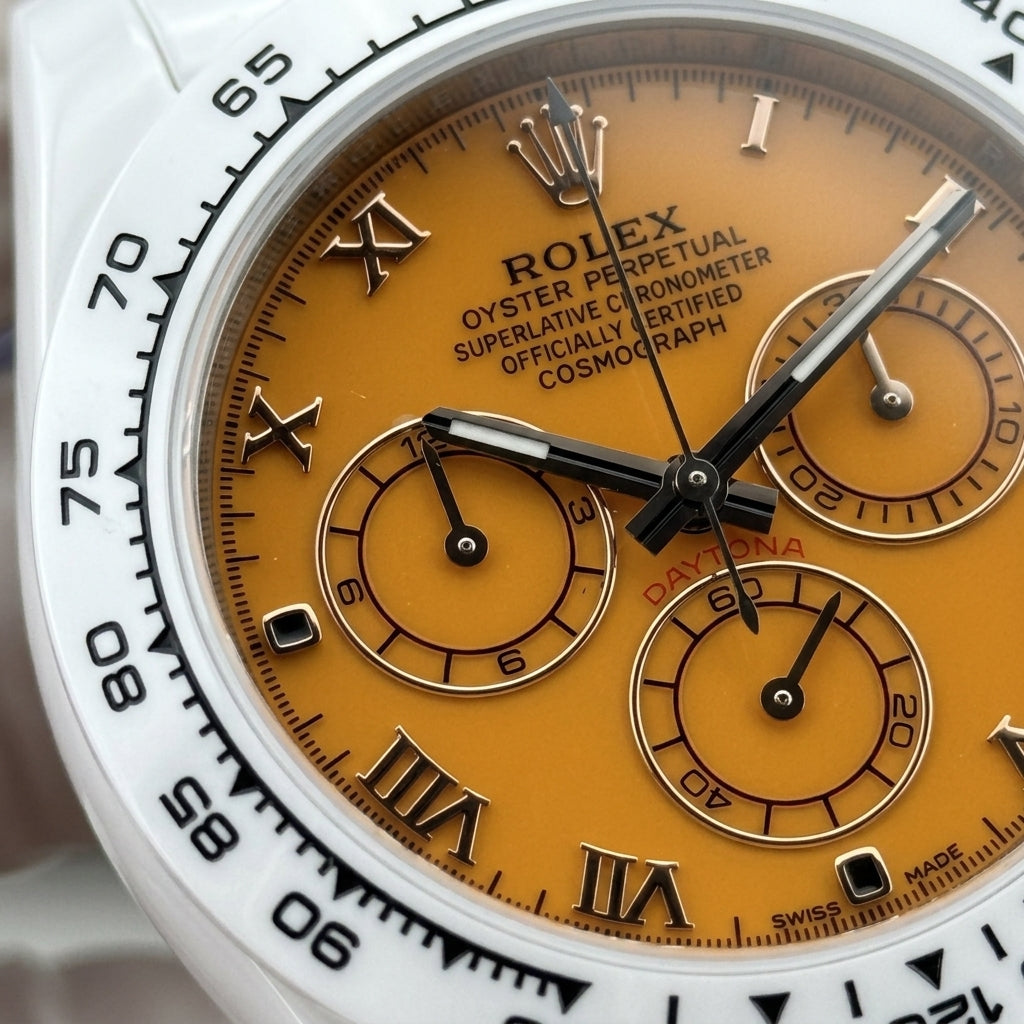 Macro of the mango-orange dial with black Roman numerals and three counters ringed in rose-gold tone