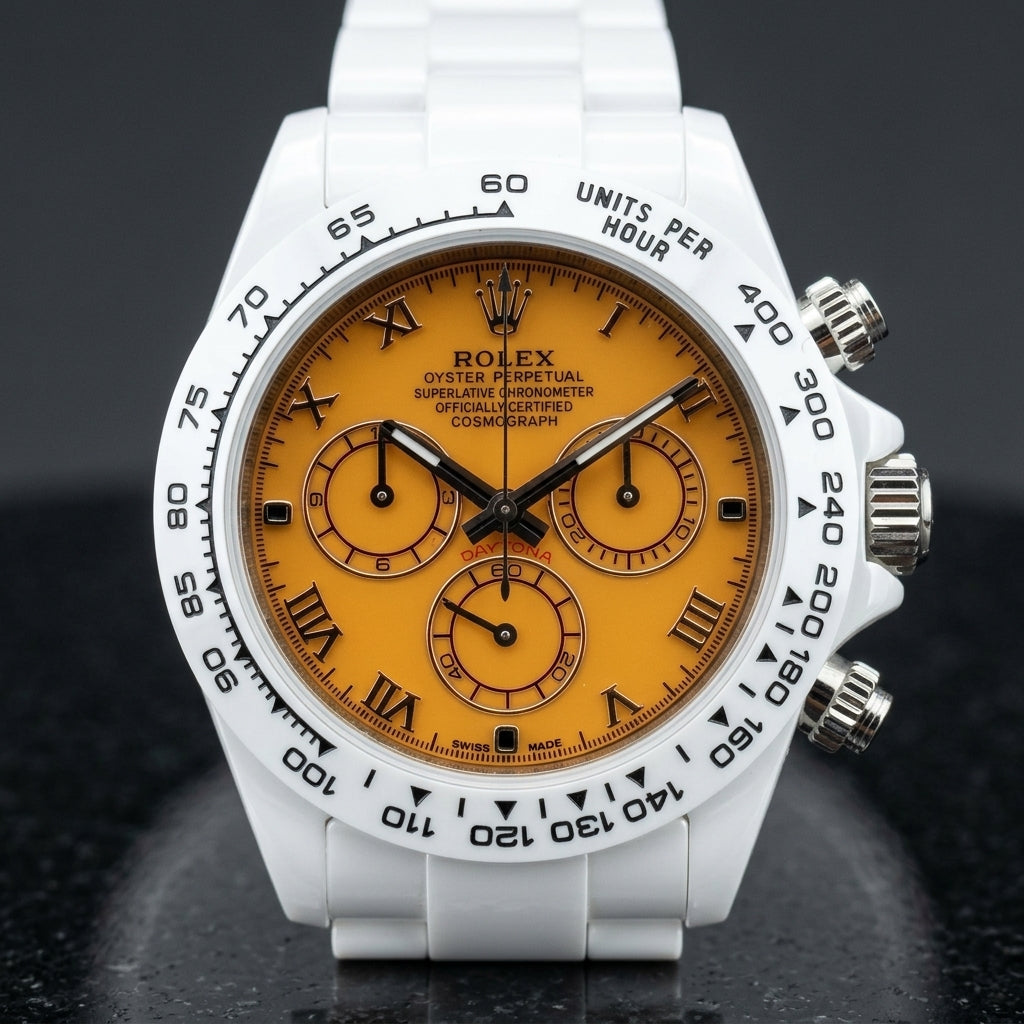 White ceramic chronograph with an orange dial on its white ceramic bracelet, worn on the wrist below a dark suit cuff
