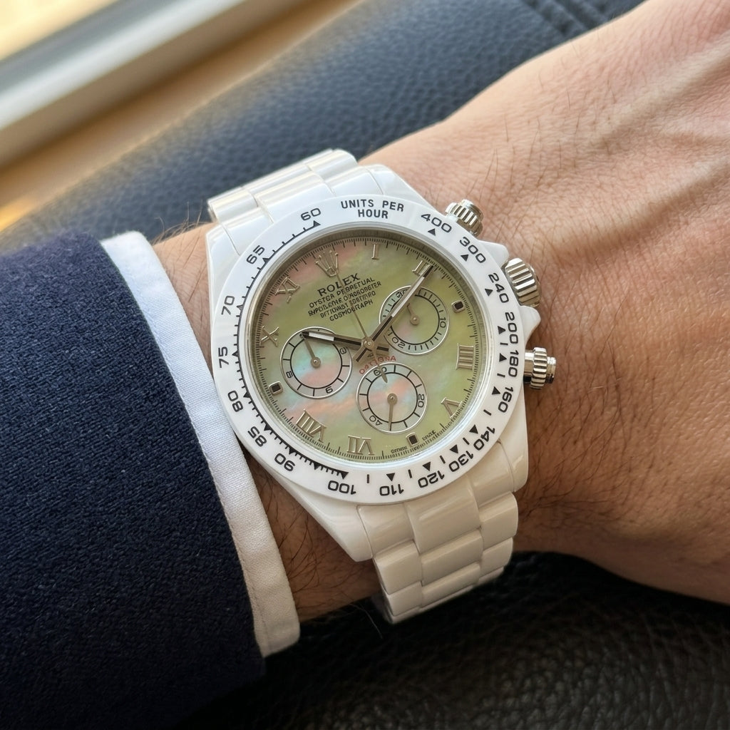 White ceramic chronograph with a green mother-of-pearl dial on the wrist below a dark suit cuff