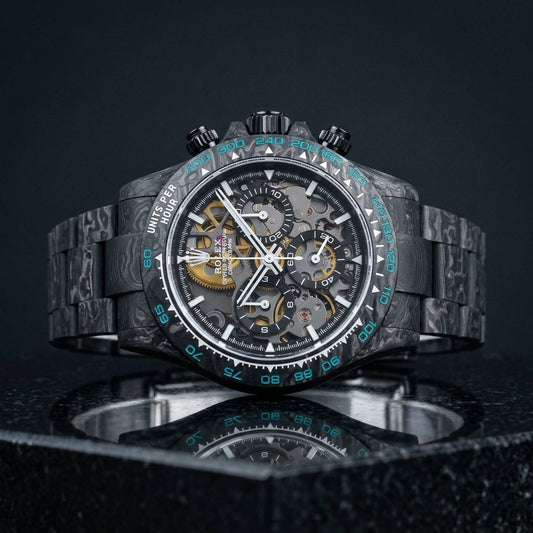 Forged carbon skeleton chronograph with cyan bezel numerals on black granite