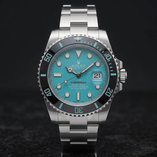 Steel dive watch with a turquoise dial and a black ceramic bezel, upright on polished black granite