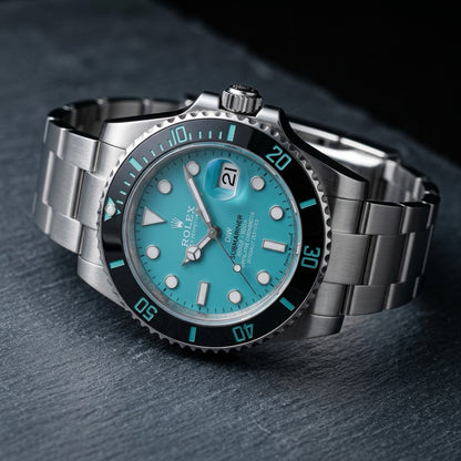 Steel dive watch at a three-quarter angle on dark slate, the screw-down crown and the coin-edge bezel