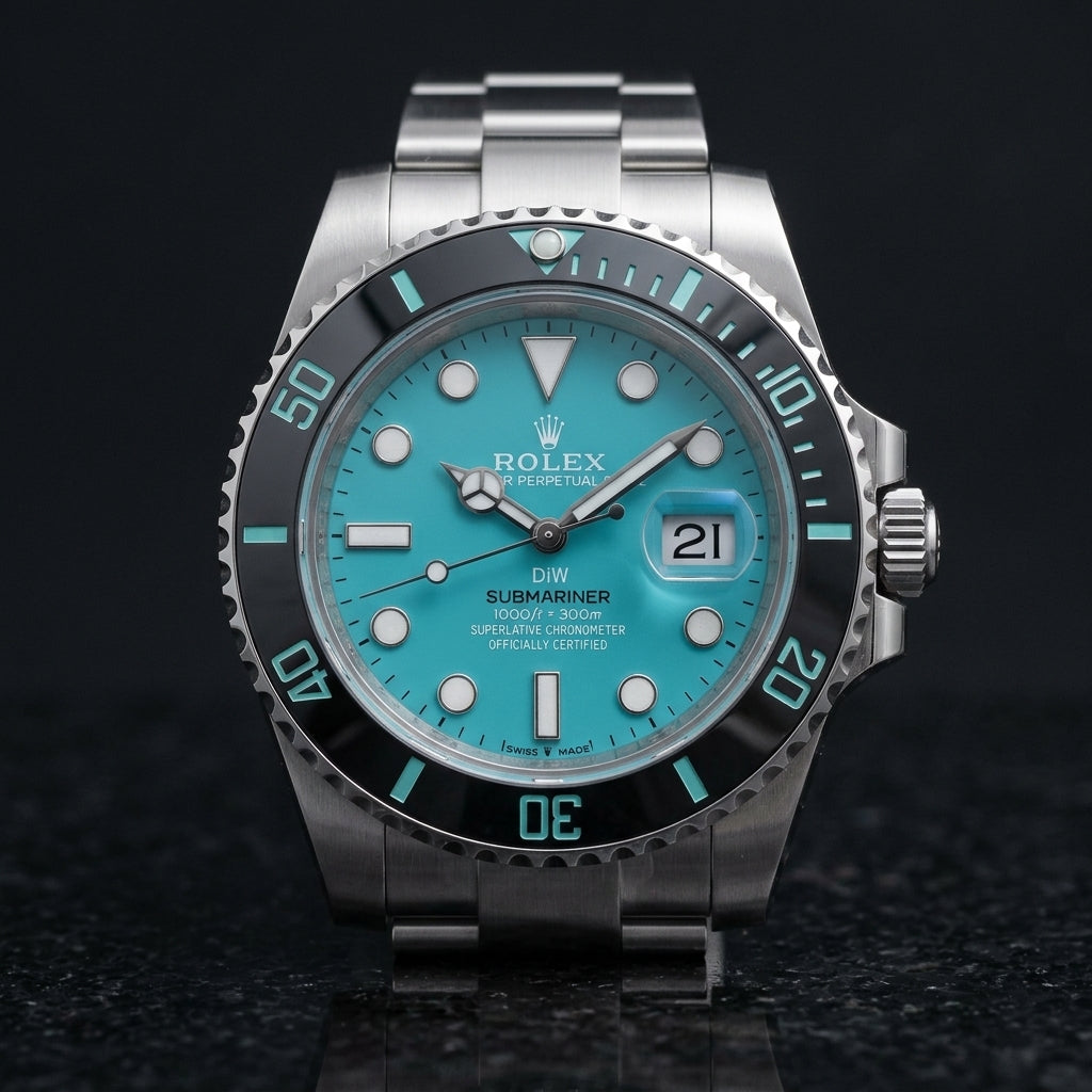 Steel dive watch with a turquoise dial on its three-link bracelet, worn on the wrist below a navy suit cuff