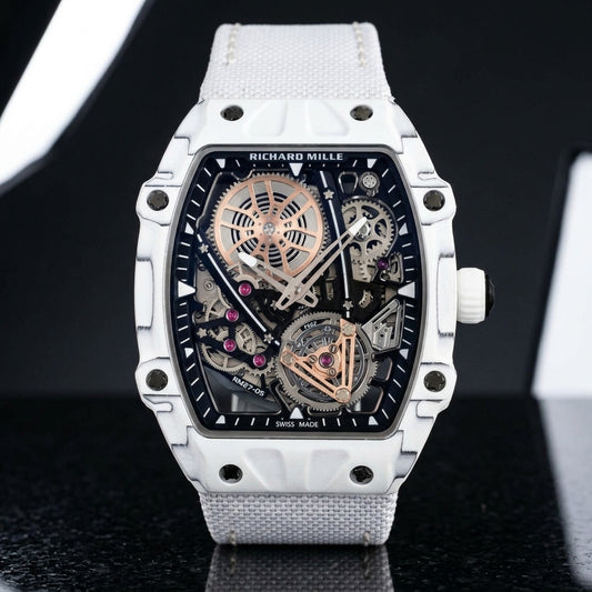 All-white thin-ply carbon tonneau watch with an open skeleton dial and a white woven strap, upright on polished black granite
