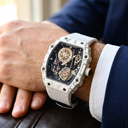 All-white carbon skeleton tourbillon watch on a white woven strap, worn on the wrist below a navy suit cuff
