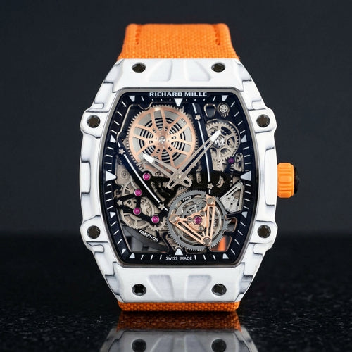 White thin-ply carbon tonneau watch with an open skeleton dial and an orange woven strap, upright on polished black granite